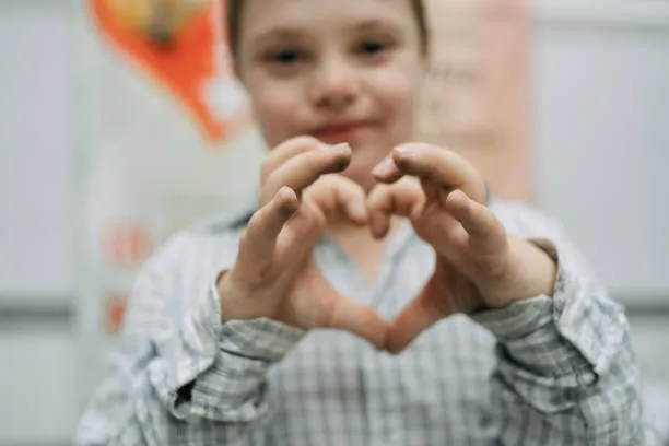 child-with-down-syndrome-making-heart-shape-with-hands